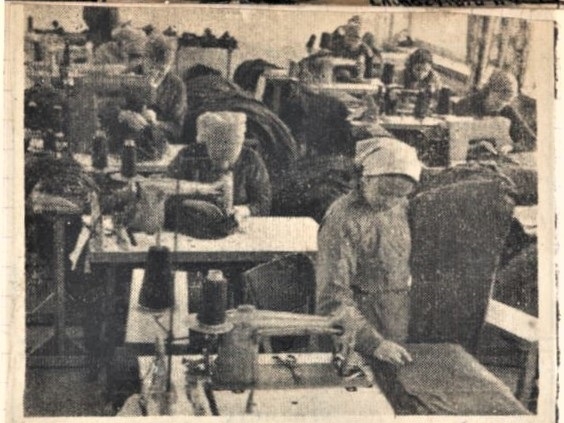 skan czarno-białego zdjęcia prasowego, na którym widać pomieszczenie szwalni, a w niej siedzących przy maszynach krawieckich pracowników