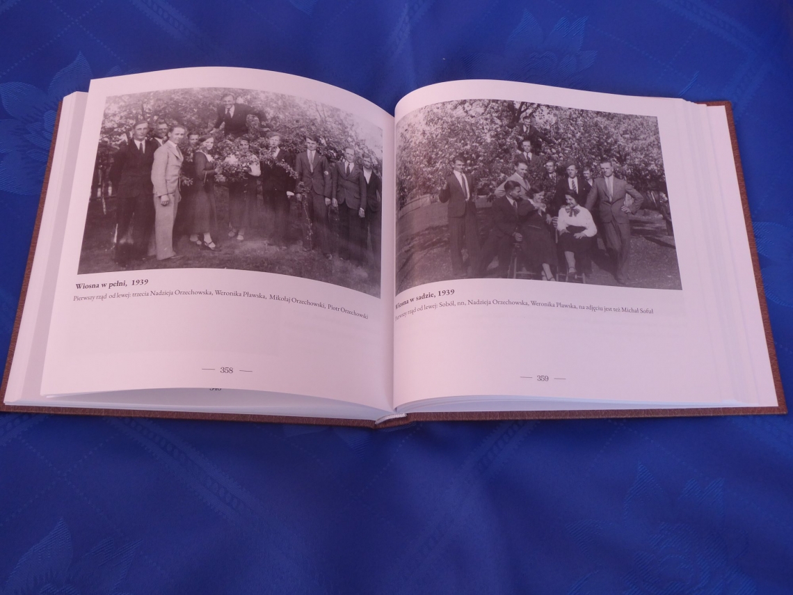 na granatowym obrusie leży otwarta książka z archiwalnymi czarno-białymi zdjęciami