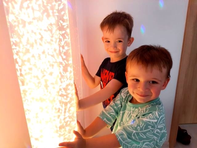 dwóch chłopców dotyka świecącej lampy w sali doświadczania świata