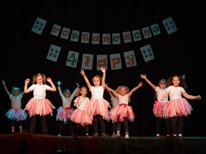 Dziewczynki w różowych spódniczkach tańćzące na scenie.