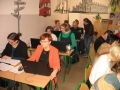 Uczestnicy szkolenia w trakcie spotkania, usadzenia są za szkolnymi ławkami, na stolikach mają laptopy
