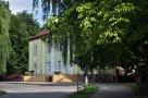 budynek Hajnowskiego Domu Kultury od frontu; wokół zielone korony drzew
