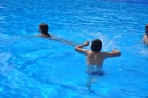 Na zdjęciu basen, w nim kąpią się trzy osoby.