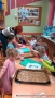 Na zdjęciu dzieci układaja na blaszki z papierem do pieczenia wykrojone pierniczki. Na stole leży kartka z napisem: Razem na święta.