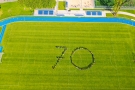 zdjęcie zrobione z góry; na zielonej murawie stadionu mieszkańcy miasta ustwili się w kształt cyfry siedemdziesiąt