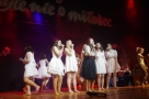 Grupa śpiewajacych dziewcząt w białych sukienkach.