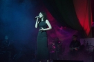 Na scenie stoi wokalistka w czarnej sukienki