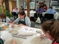 Uczestnicy warsztatów ceramicznych podczas tworzenia rzeźb z gliny.