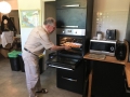 starszy mężczyzna wkłada blaszkę z kuleczkami do piekarnika