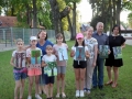 grupa uczestniów pleneru, każdy z nich trzyma w ręku namalowane przez siebie pejzaże