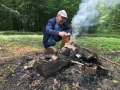 Mężczyzna rozpala ognisko w lesie.