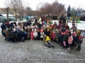 Zdjęcie grupowe całej społeczności przedszkolnej z kolędnikami na placu zabaw.