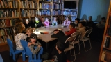 dziei siedzą przy stole w ciemnej sali biblitecznej. Na głowach mają latarki czołowe.