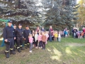  personel przedszkola wraz z dziećmi i strażakami, stojący na placu przedszkolnym.