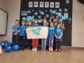 Zdjęcie grupowe przedszkolaków i nauczycielek ubranych w niebieskie koszulki.