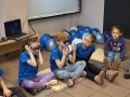Czworo dzieci siedzi na podłodze, dwie dziewczynki mają założone ciemne okulary.