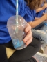 Dziecko trzyma plastikowy kubek ze słomką.