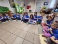 Dzieci siedzą na podłodze, trzymając plastikowe kubki.