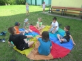 Dzieci siedzą na kolorowej chuście animacyjnej.