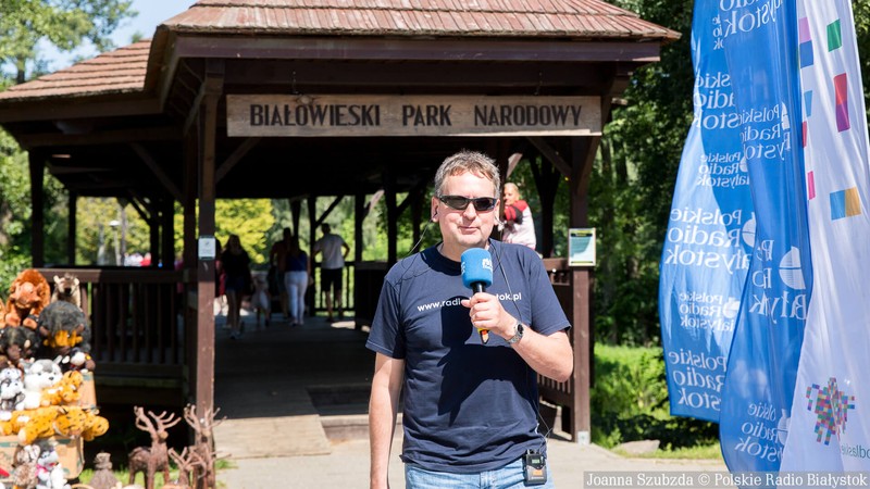 dziennikarz z Radia Białystok stoi przed bramą do Białowieskiego Parku Narodowego