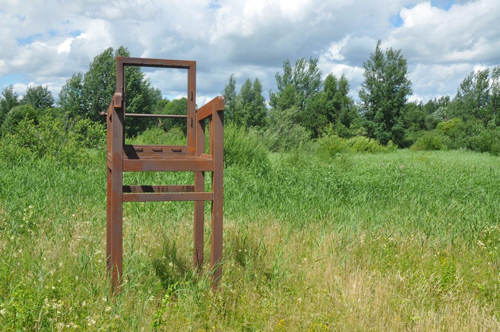 rzeźba w kształcie szkieltu fotela w otoczeniu zielonej trawy