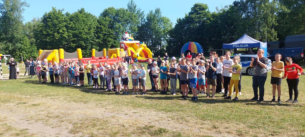 uczestnicy pikniku rodzinnego. W tle widać dmuchany plac zabaw