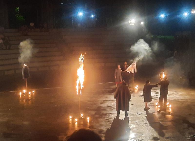 aktorzy na płycie amfiteatru, scena oswietlona ogniem