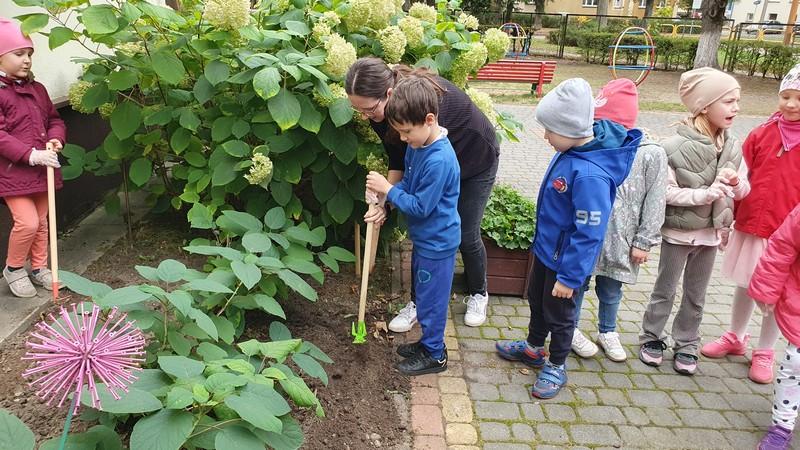 dzieci kopią w ziemi miejsce pod kwiaty