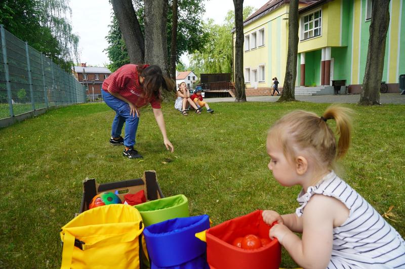 dziecko siedzi przy kolorowych torbach z piłeczkami
