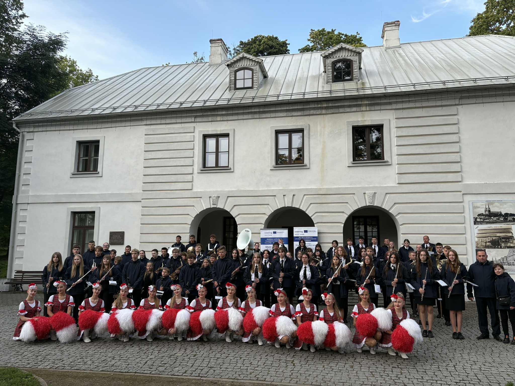 wspołne zdjęcie orkiestr polskiej i litweskiej przed białym budynkiem