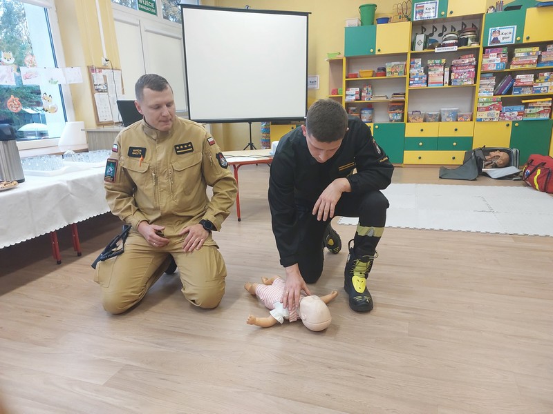 ratownicy instruują rodzic&oacute;w jak udzielić pierwszej pomocy na fantomie niemowlaka