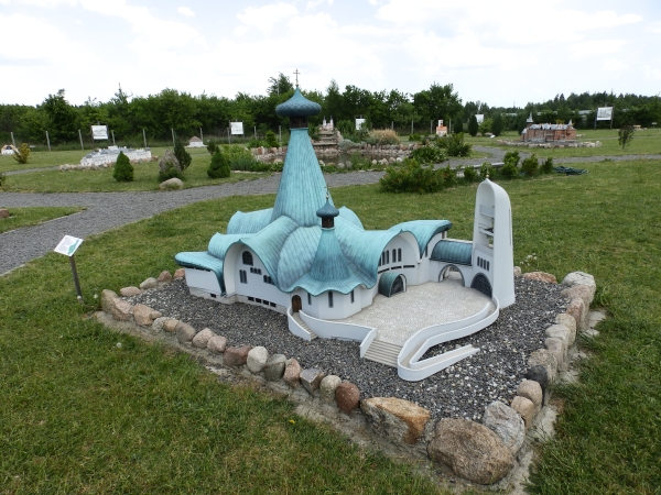 Miniatura hajnowskiego Soboru Św.Trójcy; wokół alejki wysypane drobnymi kamieniami prowadzącymi do kolejnych obiektów; pomiędzy nimi zielona trawa; przy każdej miniaturze ustawiona jest mała tabliczka z opisem obiektu
