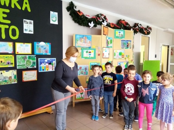 Dyrektor Przedszkola Małgorzata Saadoon, dokonuje uroczystego otwarcia wernisażu, poprzez przecięcie wstęgi trzymanej przez dzieci
