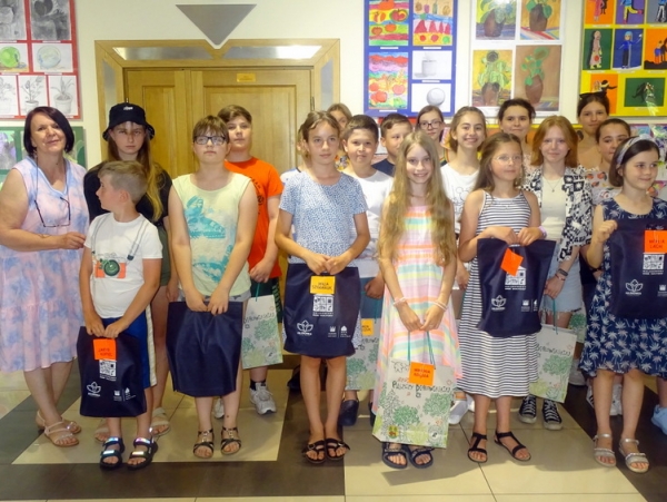 zdjęcie grupowe uczestników koła na tle wystawy ich prac