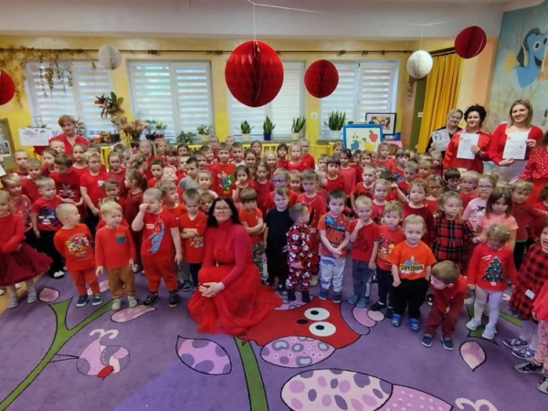 Wszyscy uczestnicy kampanii pozują do zdjęcia. Dzieci oraz kadra pedagogiczna jest ubrana na czerwono. Czerwony jest kolorem kampanii.