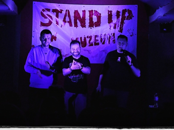 trzej mężczyźzni. W tle widać baner STAND UP