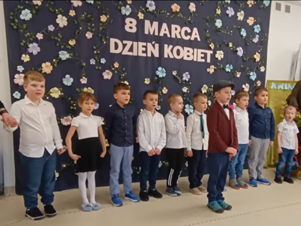 dzieci stoją przed dekoracją z okazji Dnia Kobiet