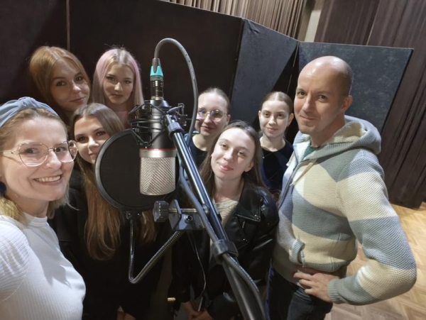 dziewczęta, instruktor i muzyk pozują do zdjecia przy mikrofonie