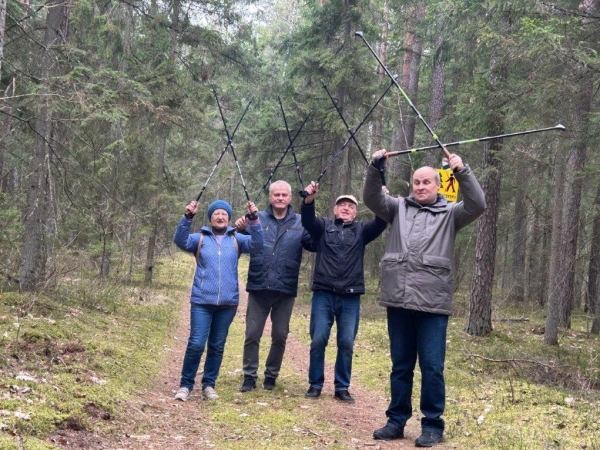 cztery osoby w lesie podnoszą kijki do góry