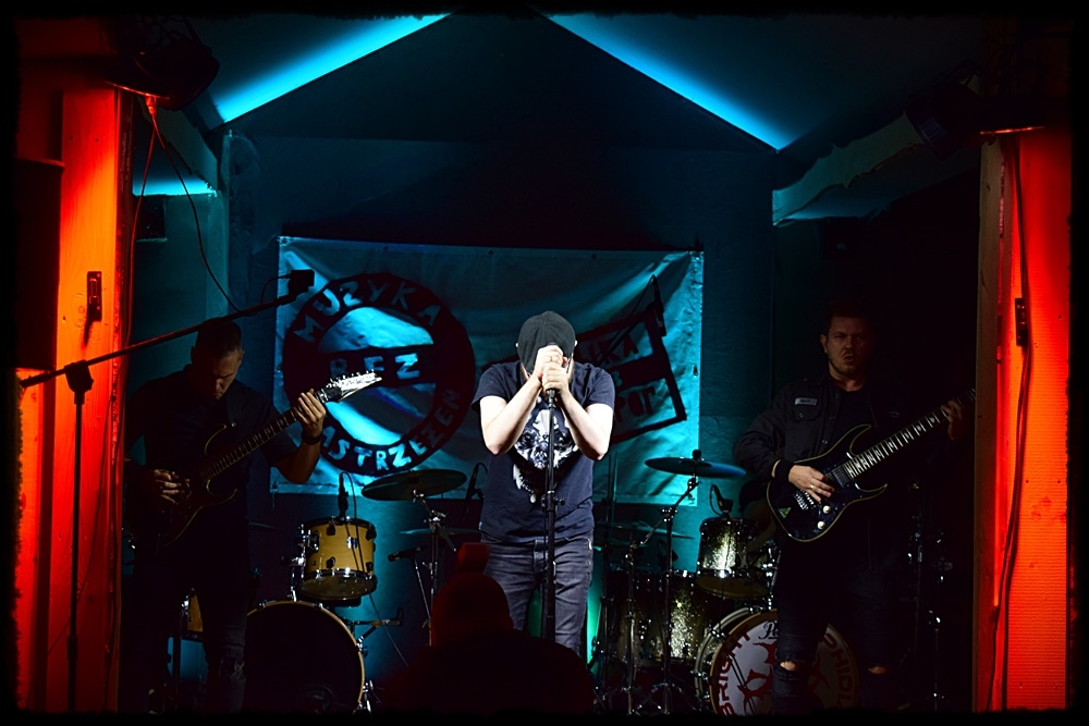 mężczyzna przy mikrofonie za nim grupa muzyków