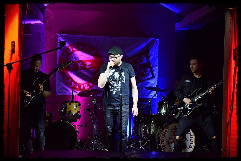 mężczyzna przy mikrofonie za nim grupa muzyków