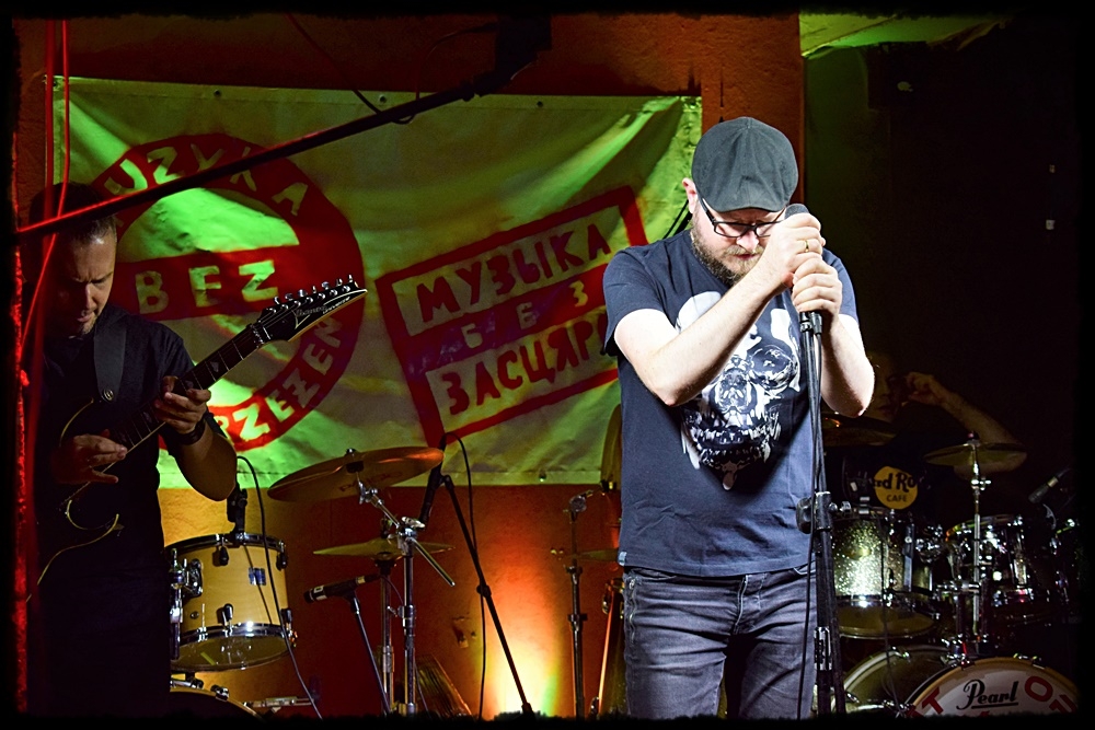 mężczyzna przy mikrofonie za nim grupa muzyków