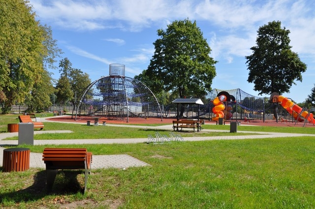 widok na wszystkie urządzenia na placy zabaw, wśrod nich piramida linowa oraz sterowiec