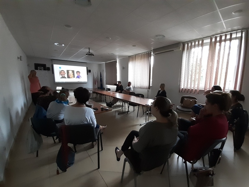 sala konferencyjna: przy stołach siedzą uczestnicy szkolenia, przed nimi prowadzący, na ścianie wisi ekran z wyświetlonym slajdem