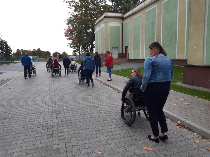 uczestnicy szkolenia podczas spaceru - część z nich jest na wózkach inwalidzkich, a przy nich asystenci