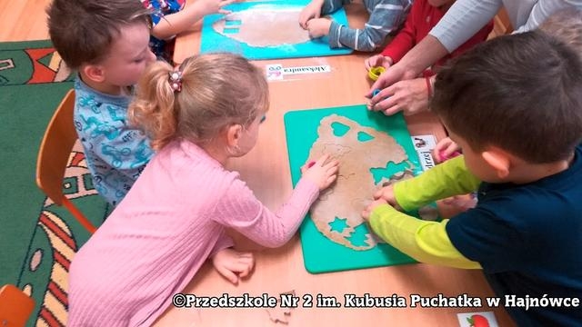 Na zdjęciu dzieci wykrawają pierniczki z rozwałkowanego ciasta, są to: serduszka, choinki, misie, gwiazdki..