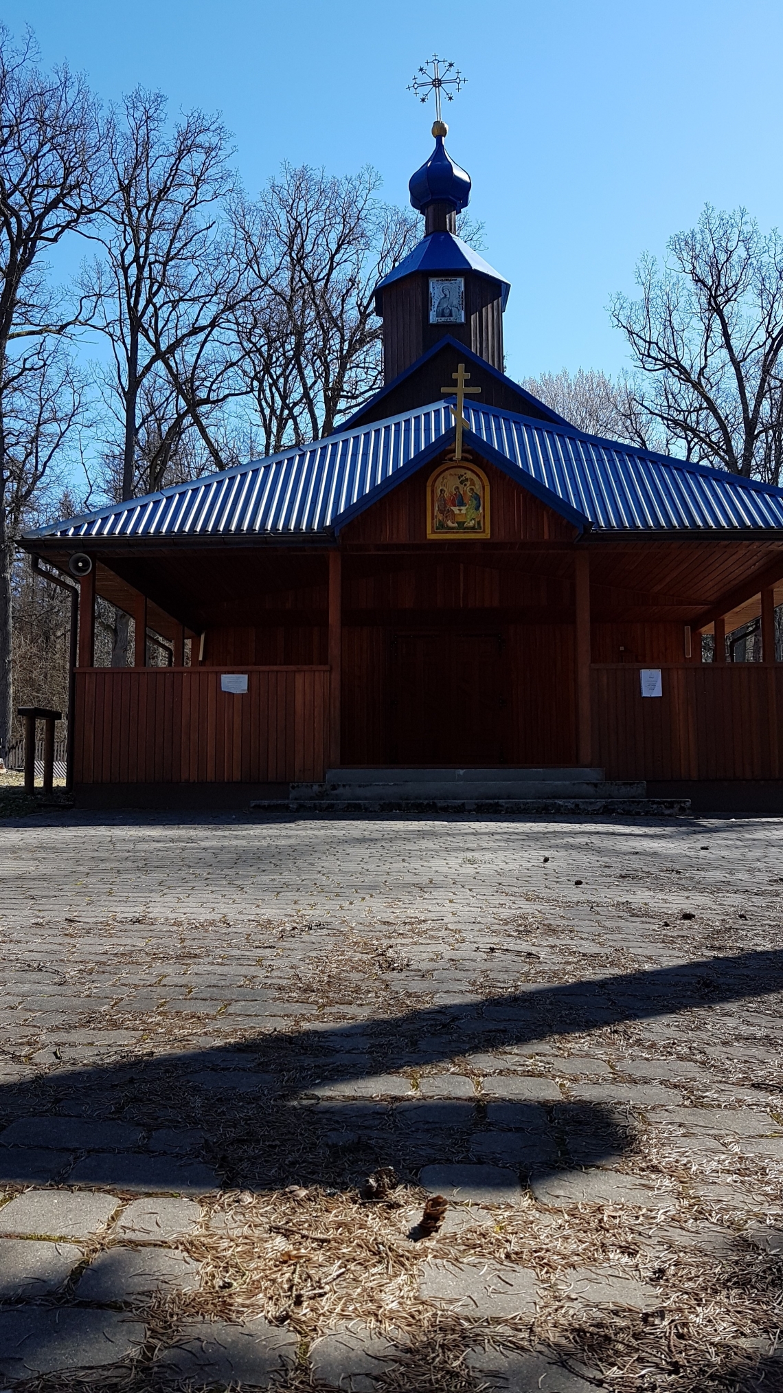 cerkiewka od przodu; widoczne jest wejście oraz kopuła; cerkiewka wybudoqwana jest z drewna, dach i kopuła pokryte są niebieską blachą