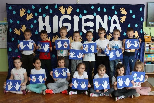 Na zdjęciu widać stojące dzieci trzymające prace plastyczne.