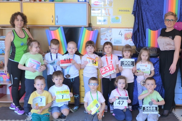 Dzieci stoją ustawione w dwóch rzędach, z brzegów stoją panie. Dzieci mają medale i numery startowe.