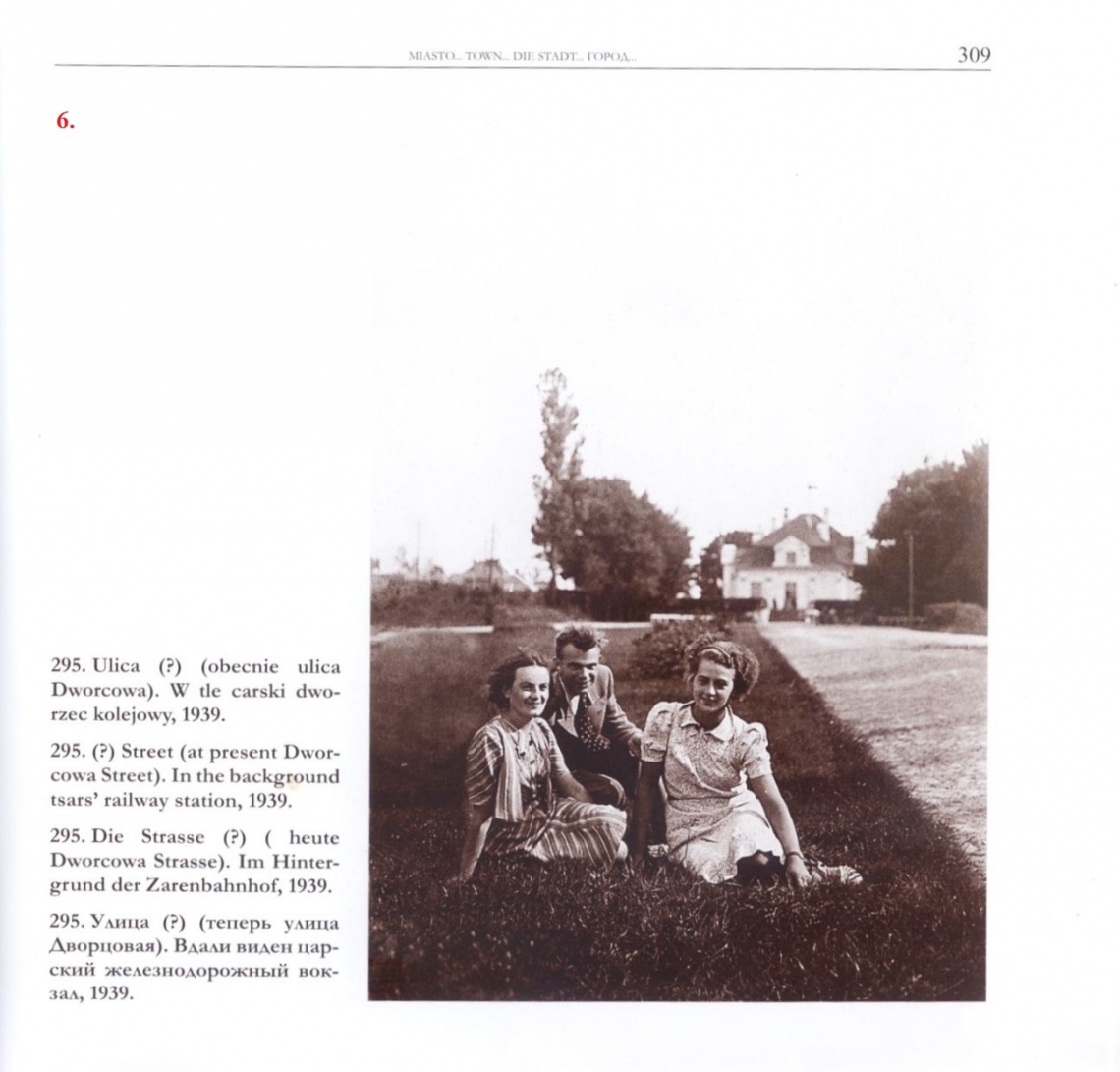 Ulica (?)  (obecnie ulica Dworcowa). W tle carski dworzec kolejowy, 1939. [tekst alternatywny: skan fotografii z albumu "Hajnówka w starej fotografii"; zdjęcie w sepii; na pierwszym planie siedzą na trawie 3 osoby, dwie kobiety i mężczyzna; w oddali widać budynek dworca]